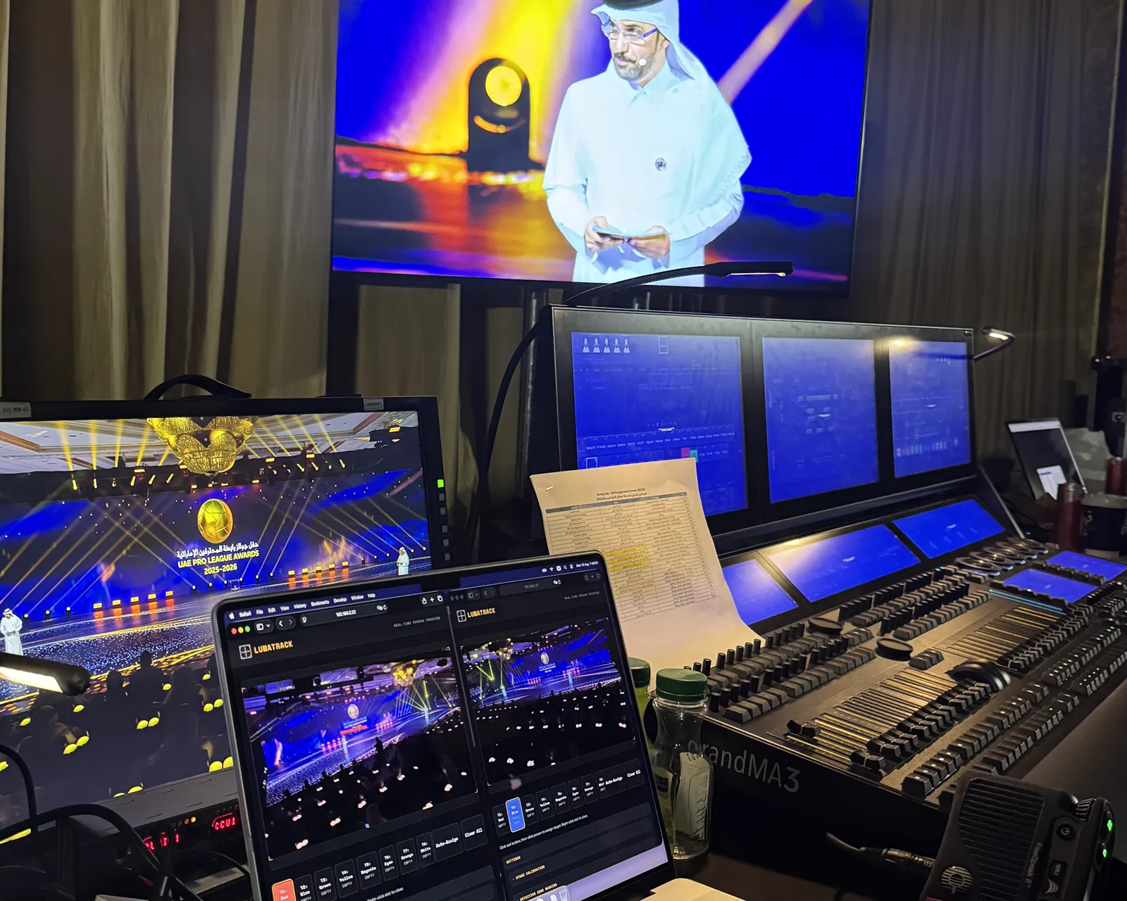 FOH at the UAE Pro League Awards — two Lumatrack tracking interfaces on the laptop beside the grandMA3 console, MC live on the broadcast monitor